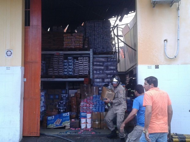 Na outra extremidade do armazém, bombeiro tentava retirar mercadoria de área que não havia sido completamente atingida pelo fogo (Foto: Luís Vítor Melo/G1)