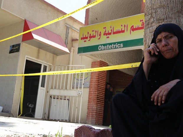 Mulher fala ao telefone em frente ao hospital Yarmuk, em Bagdá, que foi atingido por um incêndio nesta quarta-feira (10) (Foto: Sabah Arar / AFP)