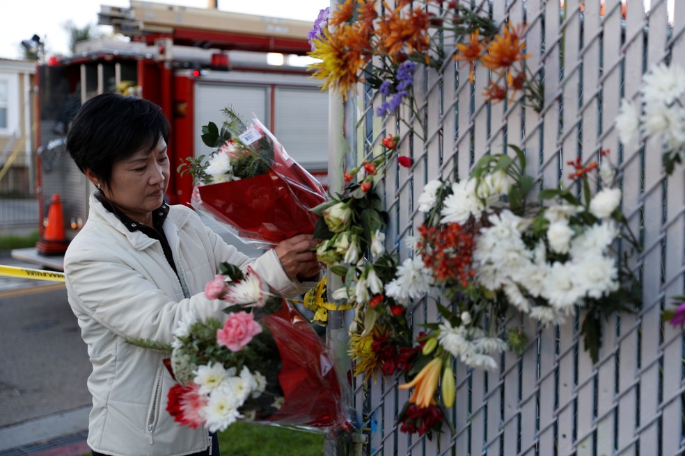 Mulher deposita flores em homenagem às vítimas de incêndio em festa na cidade de Oakland, na Califórnia, neste domingo (4) (Foto: Reuters/Stephen Lam)