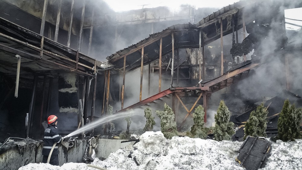 Bombeiros controlam o fogo em casa noturna na Romênia, neste sábado (21) (Foto: ISU via AP)