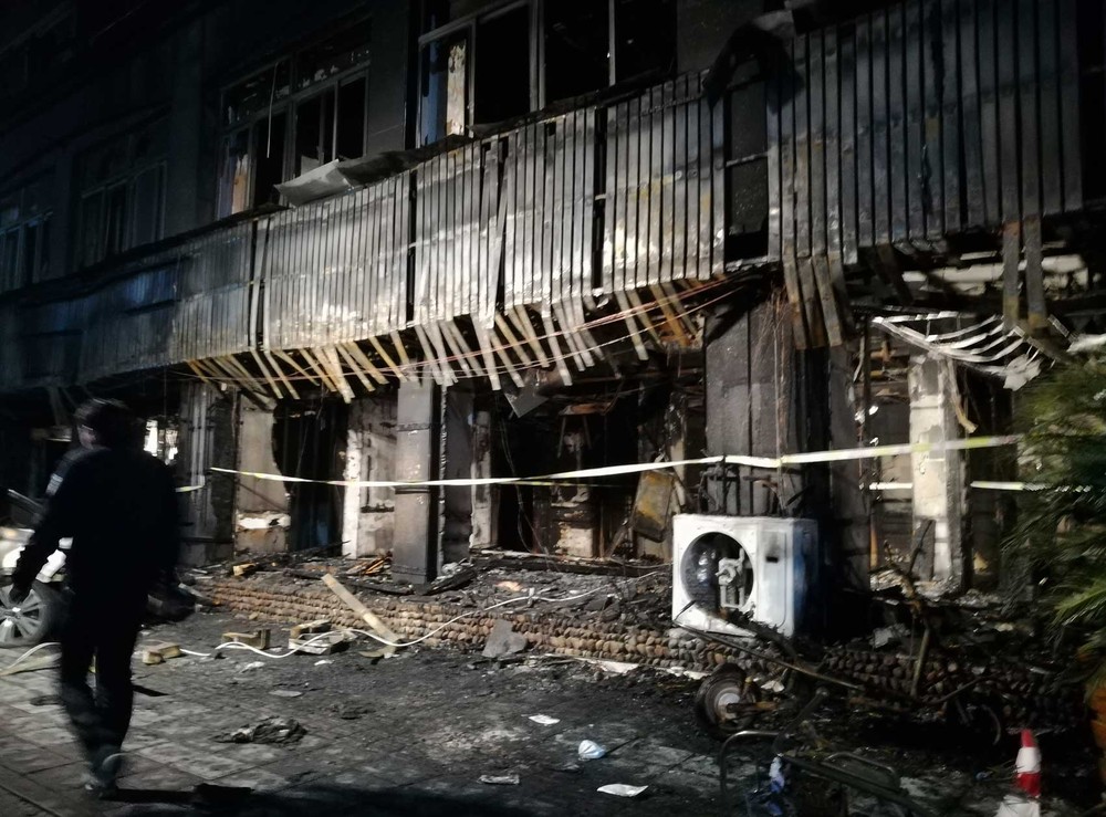 Homem passa na frente de casa de massagem que foi destruída pelo fogo na província de Zhejiang, na China (Foto: Wang Junlu/Xinhua via AP)